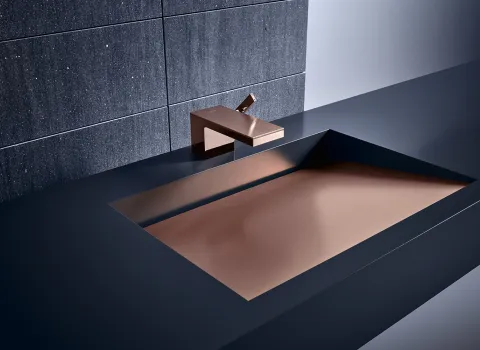 Ein elegantes Waschbecken mit einer rechteckigen Form und einer Kupfer-Innenfläche, die in einen modernen, schwarzen Waschtisch eingelassen ist. 