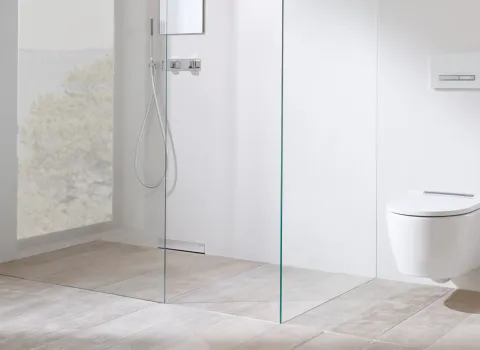 Ein modernes, minimalistisches Badezimmer mit einer bodenebenen Dusche und einer gläsernen Duschabtrennung.
