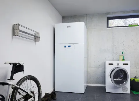 Die Inneneinheit einer Vaillant-Wärmepumpe steht in einem Hauswirtschaftsraum neben einer Waschmaschine und einem Mountainbike.