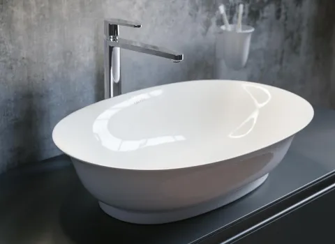 Ein elegantes, ovales Waschbecken in glänzendem Weiß steht auf einer dunkelgrauen Arbeitsfläche.