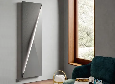 Vertikaler Polygon-Designheizkörper vom Hersteller Bemm in Anthrazit mit LED-Beleuchtung in einem modernen Wohnzimmer.