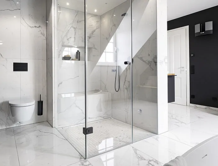Ein modernes Badezimmer mit großformatigen Marmorfliesen zeigt eine luxuriöse Dampfdusche mit gläserner Kabine.