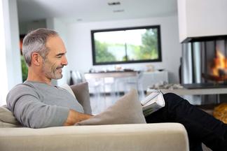 Mann im Wohnzimmer mit Kamin liest eine Zeitung